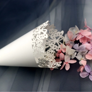 White laser cut butterfly cone for wedding flower petals on a blue fabric background