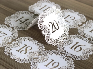 Macro shot of white laser-cut wedding table numbers with elegant floral lace details
