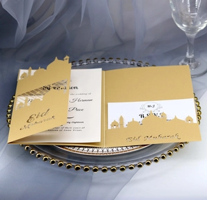 Elegant gold laser-cut Eid Mubarak invitation card with white insert on glass tray