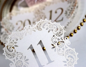 Macro detail of laser-cut wedding table card number 11 with elegant vine patterns