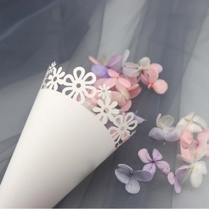Elegant white laser-cut wedding confetti cones with delicate floral patterns and petals