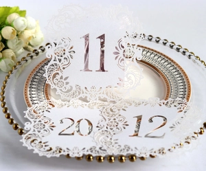 Detail of laser-cut wedding table cards with numbers 11, 12, and 20 in white lace design