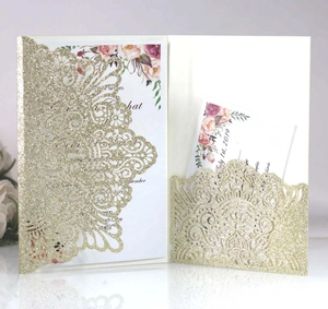 Detail of laser-cut gold glitter wedding invitation with elegant floral hollow pattern