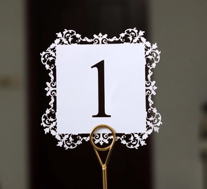 Detail of laser-cut white table number card with black digit one on a gold metal stand