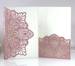 Macro detail of laser-cut wedding invitation with pink glitter mandala lace pattern