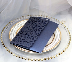 Close-up of laser cut dark blue pearl paper wedding invitation with floral hollow pattern