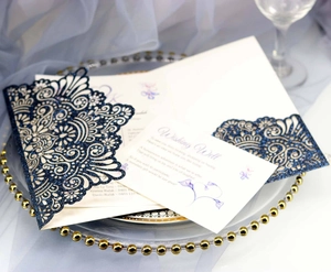 Macro view of laser-cut navy glitter invitation lace detail with floral wishing well card