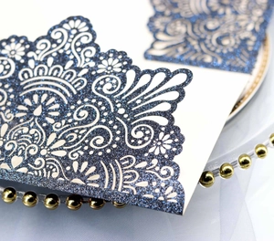 Close-up of laser-cut navy blue glitter invitation card with white mandala pattern