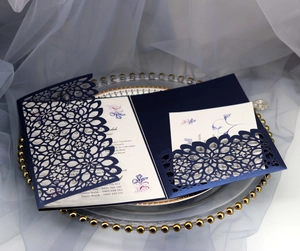 Intricate laser-cut navy blue wedding invitation with elegant floral hollow pattern