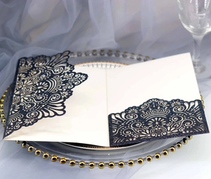 Detail of laser-cut navy blue glitter wedding invitation with elegant hollow pattern