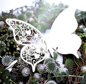 Detail of laser-cut white butterfly place card with intricate heart and leaf patterns