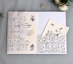 Detail of laser-cut floral invitation with elegant purple flowers on gray fabric