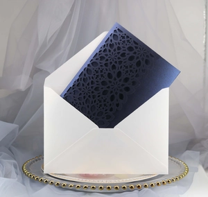Detailed laser-cut floral pattern on dark blue invitation card with white envelope