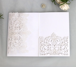 Close-up of elegant laser-cut patterns on white wedding invitation card pocket