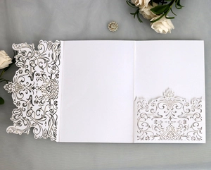 Close-up of laser-cut white lace invitation with tri-fold design and blank inner card