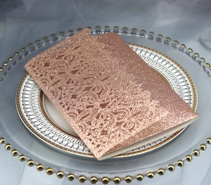 Filigrane lasergeschnittene Blumendetails auf roségoldener Glitzer-Einladungskarte