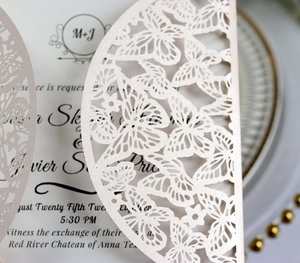 Close-up of laser-cut butterfly wedding invitation on pearlescent paper with glitter finish