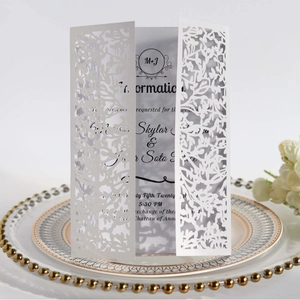 Elegant white laser-cut wedding invitation with hollow leaf patterns on decorative plate