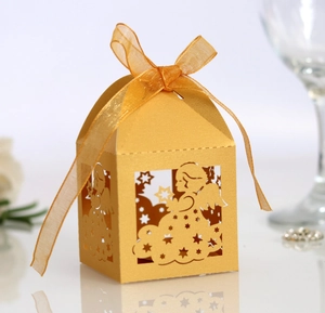 Close-up of golden laser-cut candy box with delicate angel motifs and organza ribbon