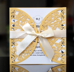 Detail of yellow laser-cut butterfly wedding invitation with cream satin ribbon and card