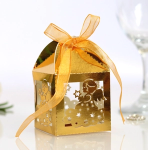 Macro shot of gold laser-cut angel gift box with shiny ribbon for wedding and party favors