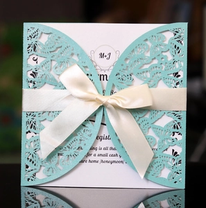 Close-up of laser-cut butterfly invitation card in Tiffany blue with a silk ribbon bow