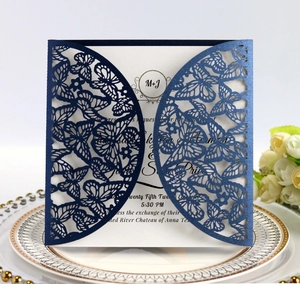 Detail of laser-cut navy wedding invitation with butterflies and white floral decor