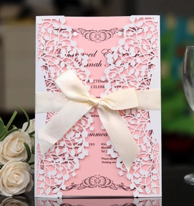 Macro shot of laser-cut leaf pattern invitation with a soft cream satin ribbon bow
