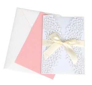 Detail of pink laser cut invitation set with elegant leaf texture and cream satin bow