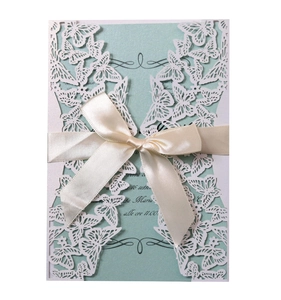 Intricate laser-cut butterfly invitation in mint green with elegant white ribbon bow