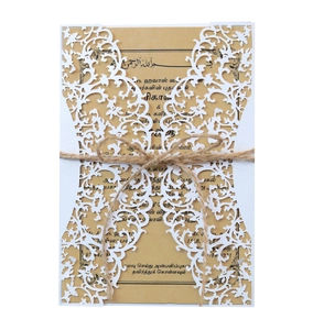 Detail of laser cut lace wedding invitation with kraft paper card and jute twine bow