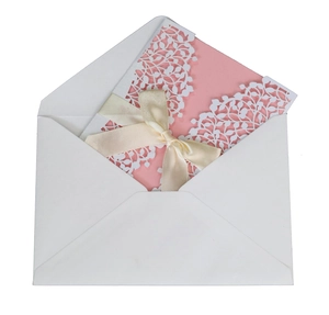 Detail of pink laser-cut leaf invitation card with white envelope and beige ribbon bow