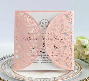 Detail of pink laser-cut butterfly invitation on a golden pattern plate with white roses