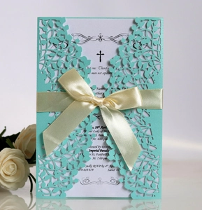 Detail of laser-cut leaf pattern invitation with cream satin bow and mint green paper