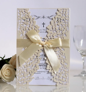 Close-up of laser-cut vine patterns on cream wedding invitation with satin ribbon