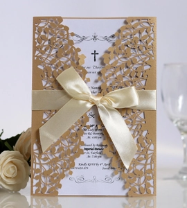 Detail of laser-cut gold foliage invitation with elegant ribbon bow and printed card