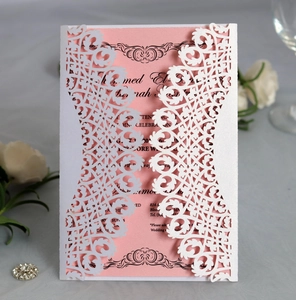 Detailed close-up of a laser-cut lace wedding invitation with pink inner card and white roses