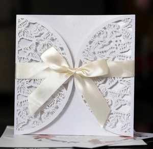 Elegant white laser-cut butterfly invitation card with a cream satin ribbon bow