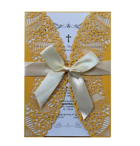 Détail macro d'une invitation de mariage découpée au laser avec motif doré et ruban