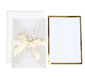 Detail of laser-cut lace wedding invitation with a cream ribbon bow and gold foil border