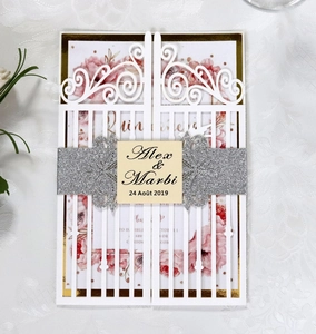 Close-up of laser-cut wedding invitation with silver glitter belt and floral inner card