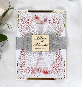 Detail of laser cut white lace wedding invitation with silver glitter belly band and tag