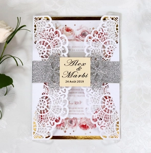 Close-up of laser cut lace wedding invitation with silver glitter belt and floral inner page
