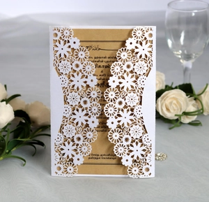 Detailed laser-cut sunflower pattern on white wedding invitation with kraft insert