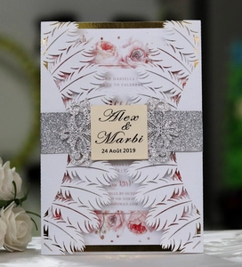 Detail of laser-cut white wedding invitation with glitter belly band and gold foil edges