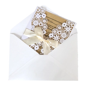 Elegant white laser cut floral wedding invitation with brown card and cream ribbon bow