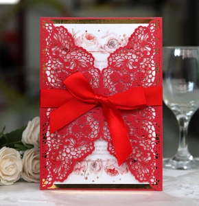 Detailed laser-cut red wedding invitation with elegant floral insert and satin ribbon
