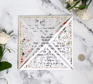 Elegante invito di nozze bianco tagliato al laser con motivi di rose su fondo in marmo