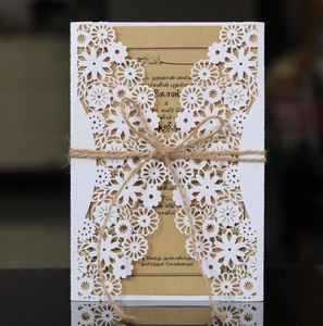 Detail of laser cut floral wedding invitation with kraft card and rustic twine bow