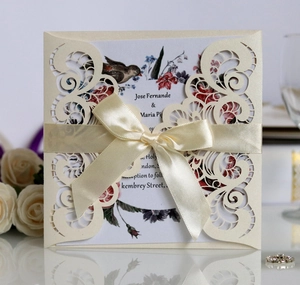 Detailed view of laser-cut wedding invitation with elegant ribbon and floral inner sheet